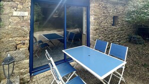 A stone building with a blue door and a table with blue chairs outside.