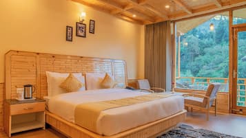 Un dormitorio con cabecera de madera, una cama grande, una mesita de noche con cafetera, una silla y vistas al exterior a través de un ventanal.