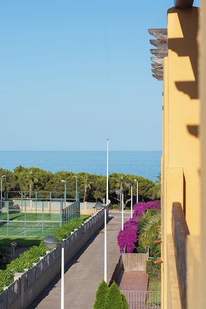 A pathway leading to a tennis court with a view of the sea.