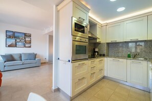A modern kitchen with built-in appliances, a dining area with a sofa, and a wall with framed pictures.