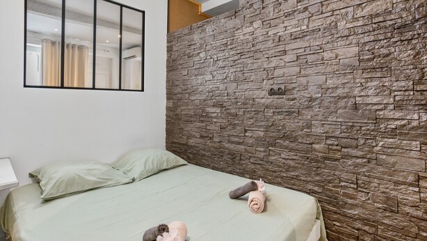 Une chambre à coucher avec un lit, des oreillers, un climatiseur fixé au mur et un miroir.