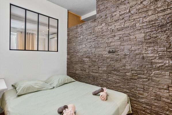 Un dormitorio con cama, almohadas, un aire acondicionado de pared y un espejo.