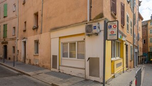 Une vue de rue avec un bâtiment sur lequel on peut voir une enseigne indiquant qu’un commerce est fermé, un passage piéton et un auvent jaune.
