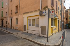 Vista de calle con un edificio que tiene una tienda cerrada, un paso de peatones y un toldo amarillo.