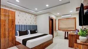 A modern hotel room with a large bed, wooden wardrobe, a small desk, and an air conditioning unit. - Super Collection O AIIMS Bhubaneshwar (Bhubaneshwar)