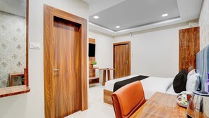 A hotel room with a bed, a dining table, a chair, and wooden doors. - Super Collection O AIIMS Bhubaneshwar (Bhubaneshwar)
