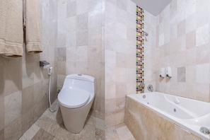 Un baño con inodoro, bañera y pared de ducha con azulejos.