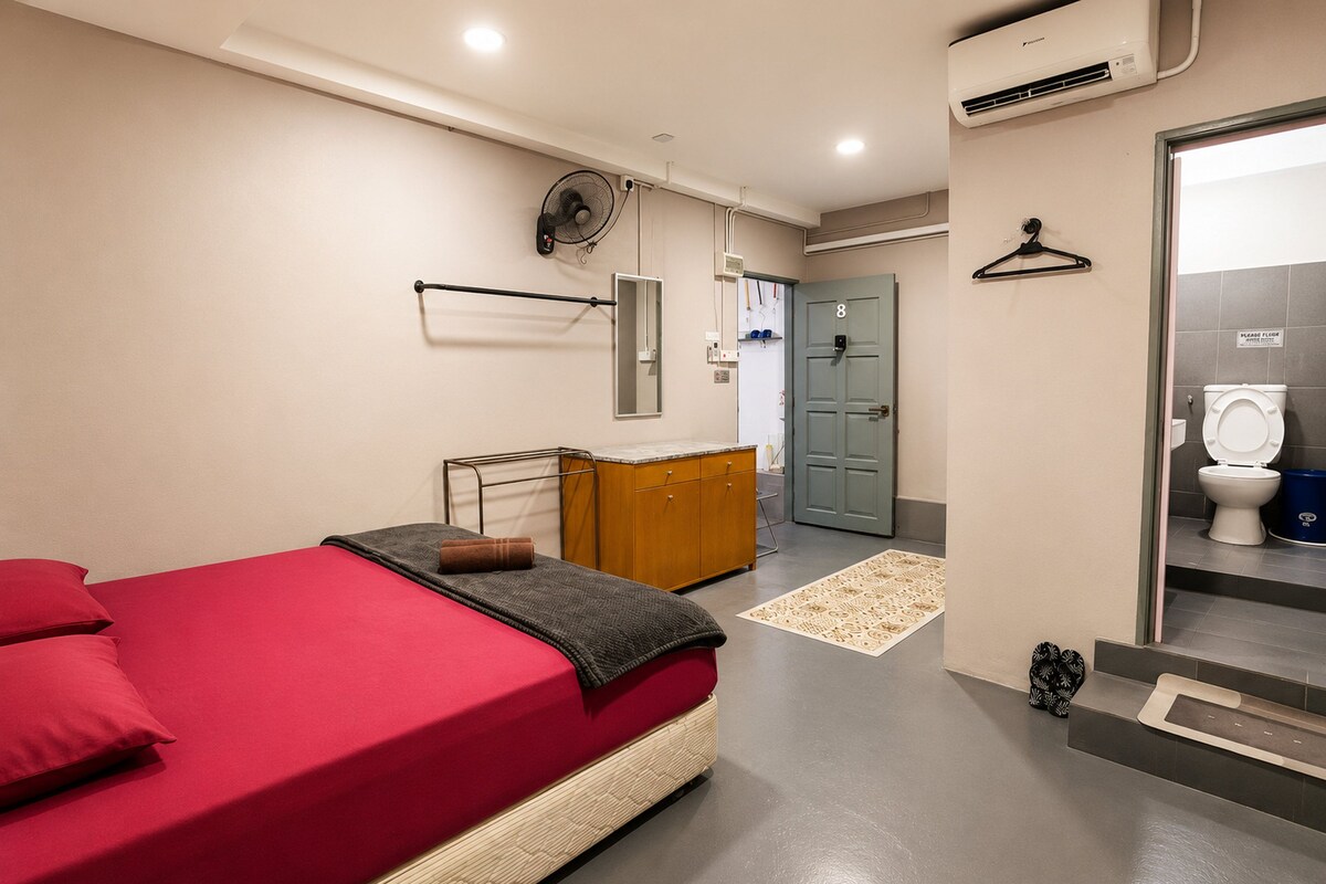A hotel room with a bed, a dresser, a mirror, a door, and a bathroom.