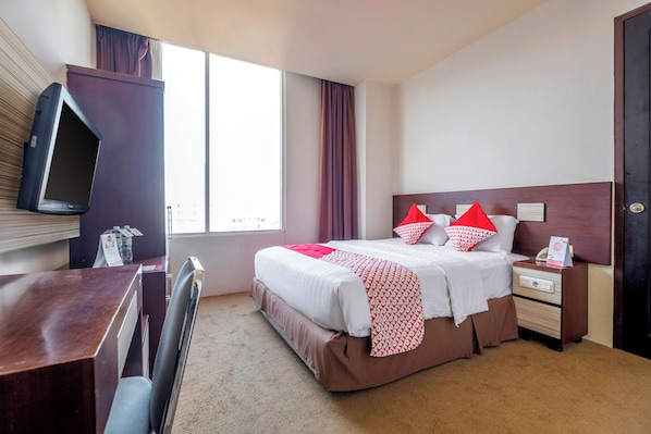 Una habitación de hotel con cama, mesita de noche y televisión montada en la pared.