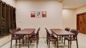 A dining area with a table and chairs, a wall-mounted air conditioner, and a door. - Collection O Ravi Talkies Bhubaneswar (Bhubaneshwar)