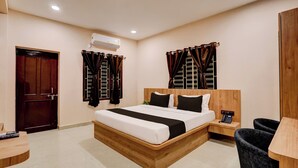 A hotel room with a wooden bed, a bedside table, a chair, a desk, and a telephone. - Collection O Ravi Talkies Bhubaneswar (Bhubaneshwar)