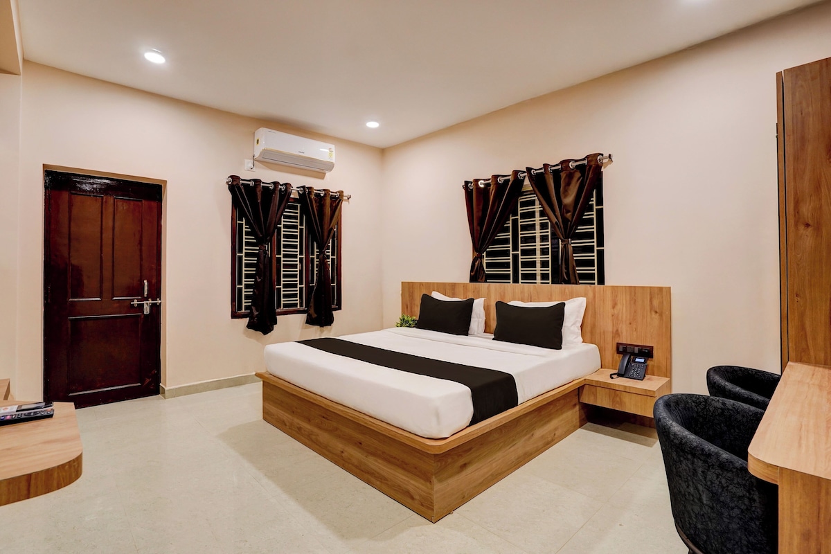 A hotel room with a wooden bed, a bedside table, a chair, a desk, and a telephone.