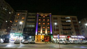 Un hotel con una entrada destacada, varios pisos y un estacionamiento lleno de autos.