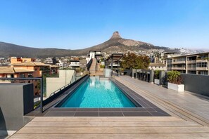 Une piscine sur le toit offrant une vue sur une montagne et des immeubles résidentiels.