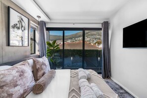 Ein modernes Schlafzimmer mit einem großen Bett, einem Flachbildfernseher und einem Balkon mit Blick auf die Stadt.