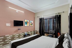 A hotel room with a bed, a flat-screen TV, artwork on the wall, a window with curtains, and a tiled backsplash. - Super Collection O ITER Bhubaneswar (Bhubaneshwar)