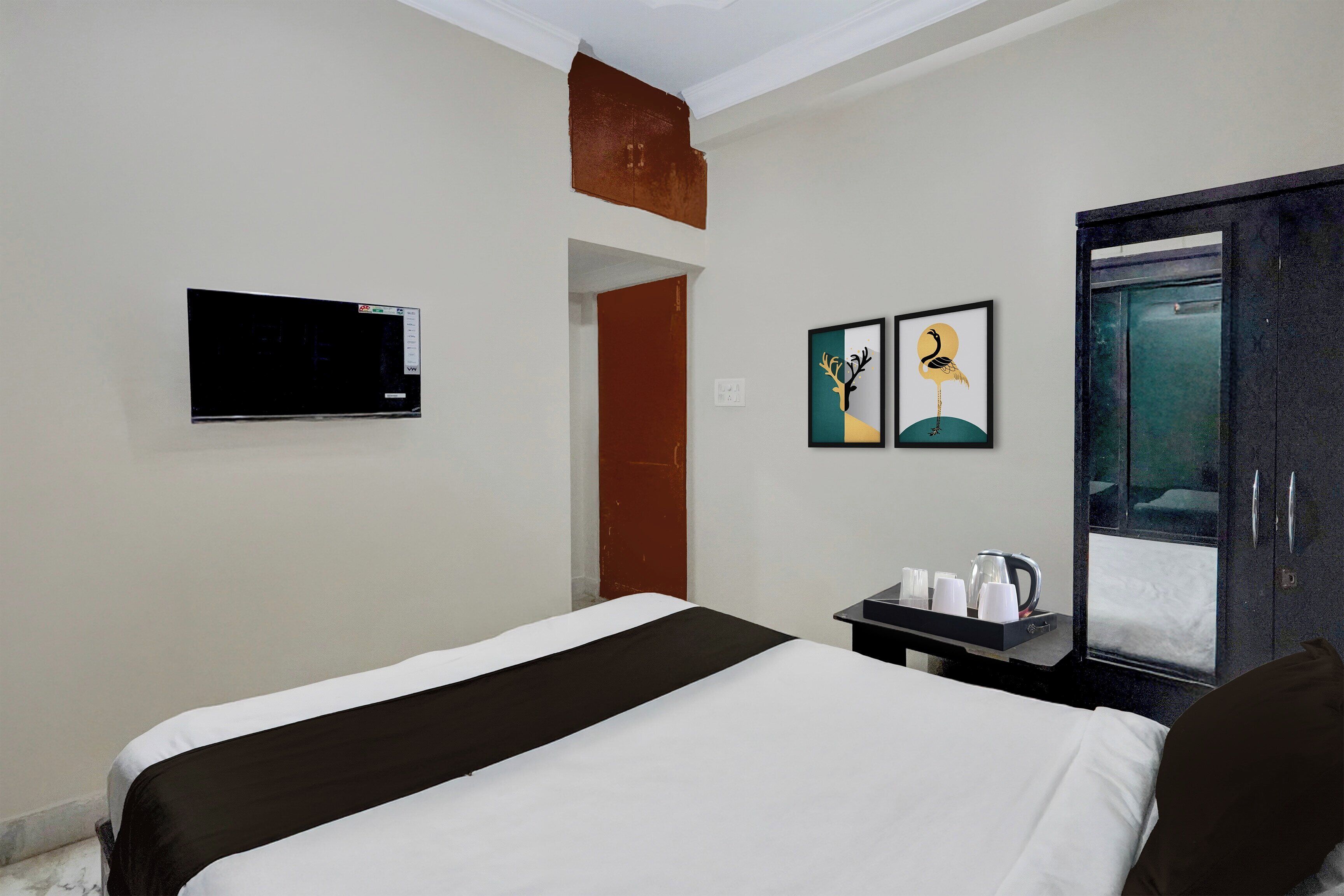 Een hotelkamer met een bed, een aan de muur bevestigde televisie en kunstwerken aan de muur.