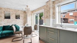 Een moderne keuken met een marmeren spatwand, een zithoek met een groene bank, en uitzicht op de omgeving.