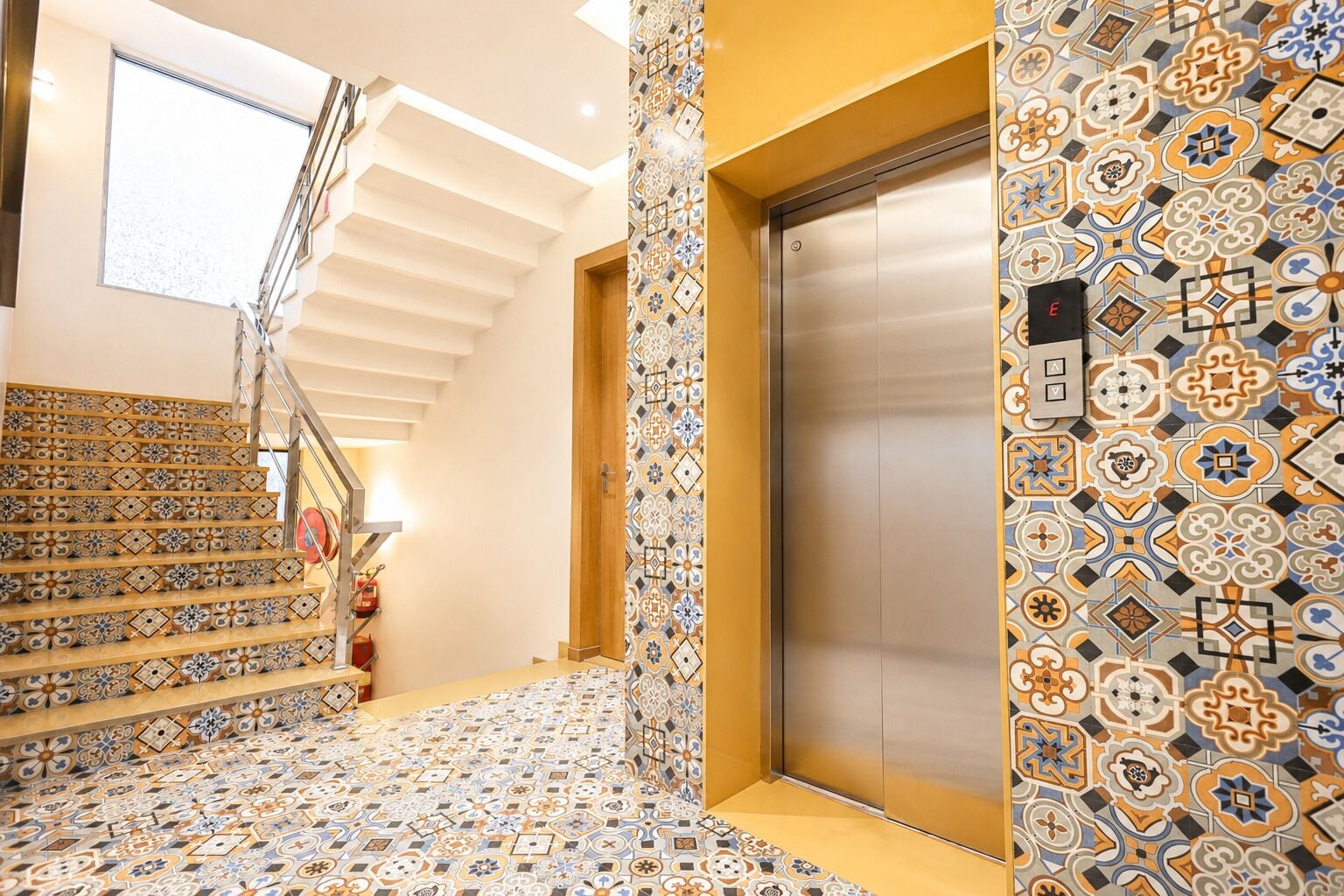A staircase with patterned tiles leading to an elevator.