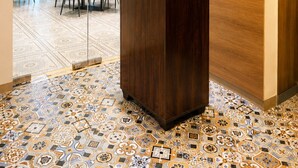 Una recepción con un mostrador de madera, una separacion de vidrio y piso de baldosas.