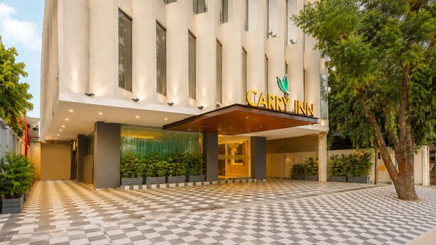 Entrada de hotel con piso a cuadros, un amplio toldo de acceso y un letrero que dice 'CARRY INN'.