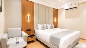 Habitación de hotel con cama, zona de estar con mesa, una botella de agua y equipo de aire acondicionado.