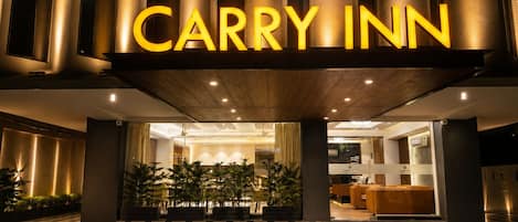 The exterior of a hotel with a prominent 'CARRY INN' sign and a checkered floor pattern.