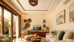 Una sala moderna con sofá, sillón y mesa de centro, televisión y obras de arte en la pared.