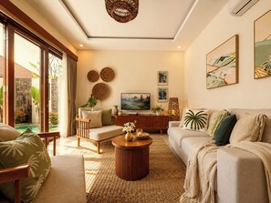 A modern living room with a sofa, armchair, and coffee table, a television, and artwork on the wall. - 2 Bedroom Pavilion Pool Villa Canggu (Bali)
