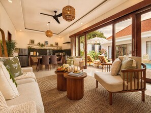 A spacious living room with a sofa, armchairs, a coffee table, and a dining area with chairs and a kitchen in the background. - 2 Bedroom Pavilion Pool Villa Canggu (Bali)