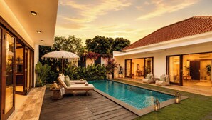 Una casa moderna con piscina, mobiliario exterior y un jardín bien cuidado.