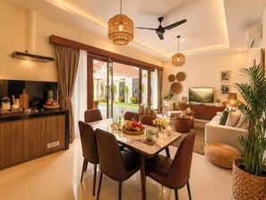 A modern living room with a flat-screen TV, comfortable seating, and a dining area with a table set for four. - 2 Bedroom Pavilion Pool Villa Canggu (Bali)