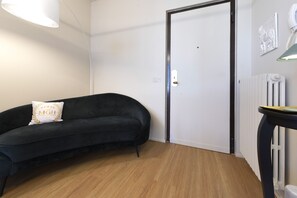 A room with a black sofa, a white door, a radiator, and a small table with a lamp. - MGH - Salò Urban Retreat (Salò)