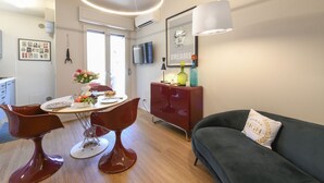 En moderne stue med spiseområde, en sofa og et fjernsyn ophængt på væggen.