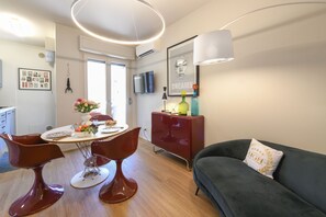 A modern living room with a dining area, a sofa, and a TV mounted on the wall. - MGH - Salò Urban Retreat (Salò)