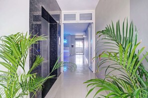 A hallway with a marble floor, glass doors, and potted plants. - Super Collection O Guwahati ISBT (Guwahati)