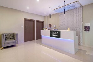 A reception area with a modern design, featuring a reception desk, a sofa, and a wall-mounted key display. - Super Collection O Guwahati ISBT (Guwahati)