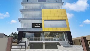 A multi-story building with a glass facade, a prominent yellow section, and a sign indicating it is a company-serviced collection. - Super Collection O Guwahati ISBT (Guwahati)