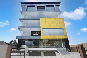 A multi-story building with a glass facade, a prominent yellow section, and a sign indicating it is a company-serviced collection. - Super Collection O Guwahati ISBT (Guwahati)