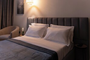 Una habitación de hotel con cama, una silla, una mesita de noche y una lámpara de pared.