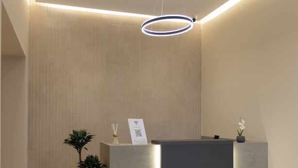 Una moderna recepción con diseño minimalista, una planta en maceta y un letrero con un código QR.
