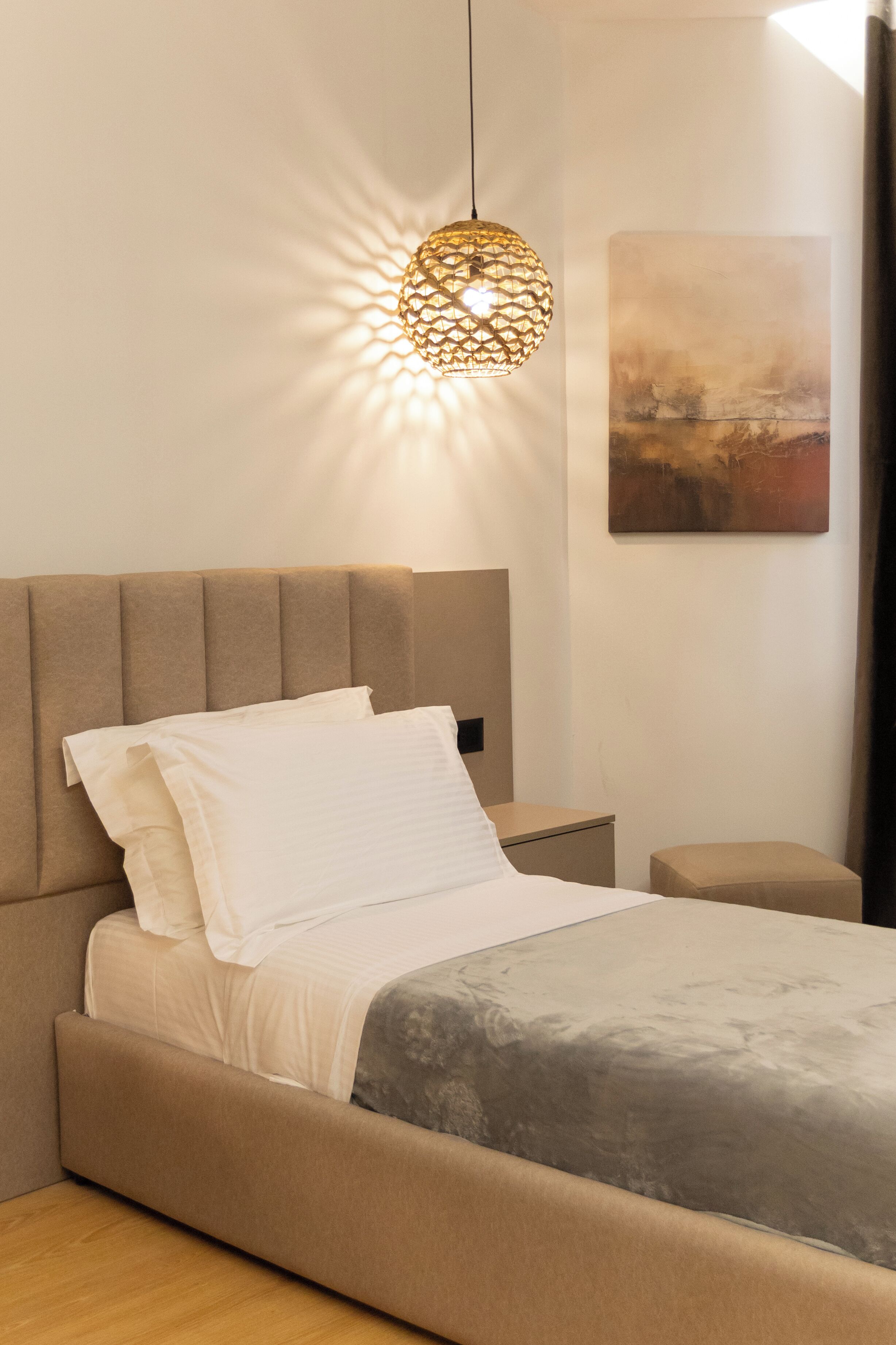 Una camera da letto con un letto, un comodino, una lampada a parete e un quadro.