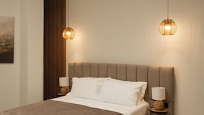 Habitación de hotel con cama, dos lámparas de noche, cabecero y una obra de arte colgada en la pared.