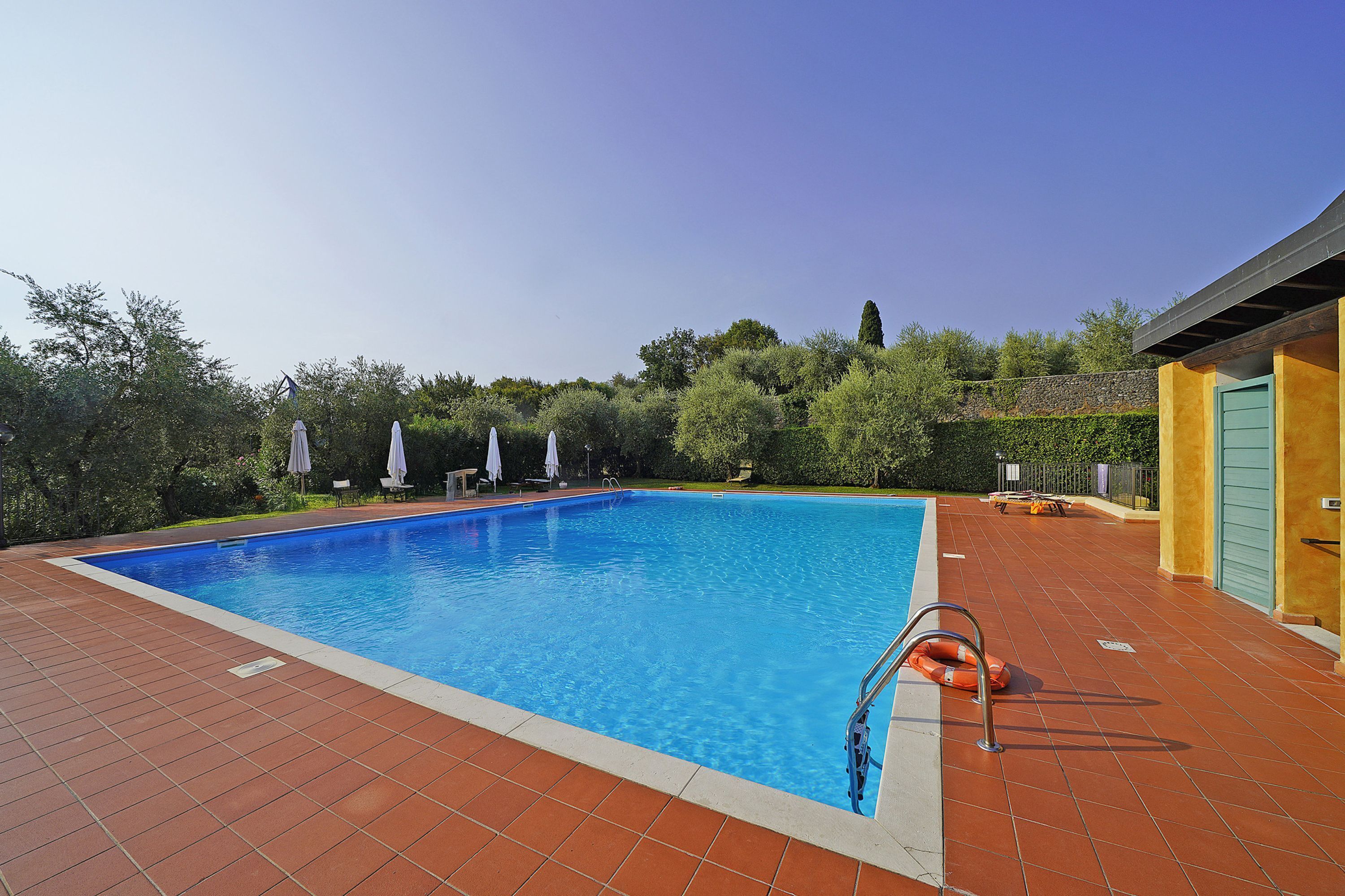 A rectangular swimming pool with a clear blue water surface, surrounded by a tiled deck.