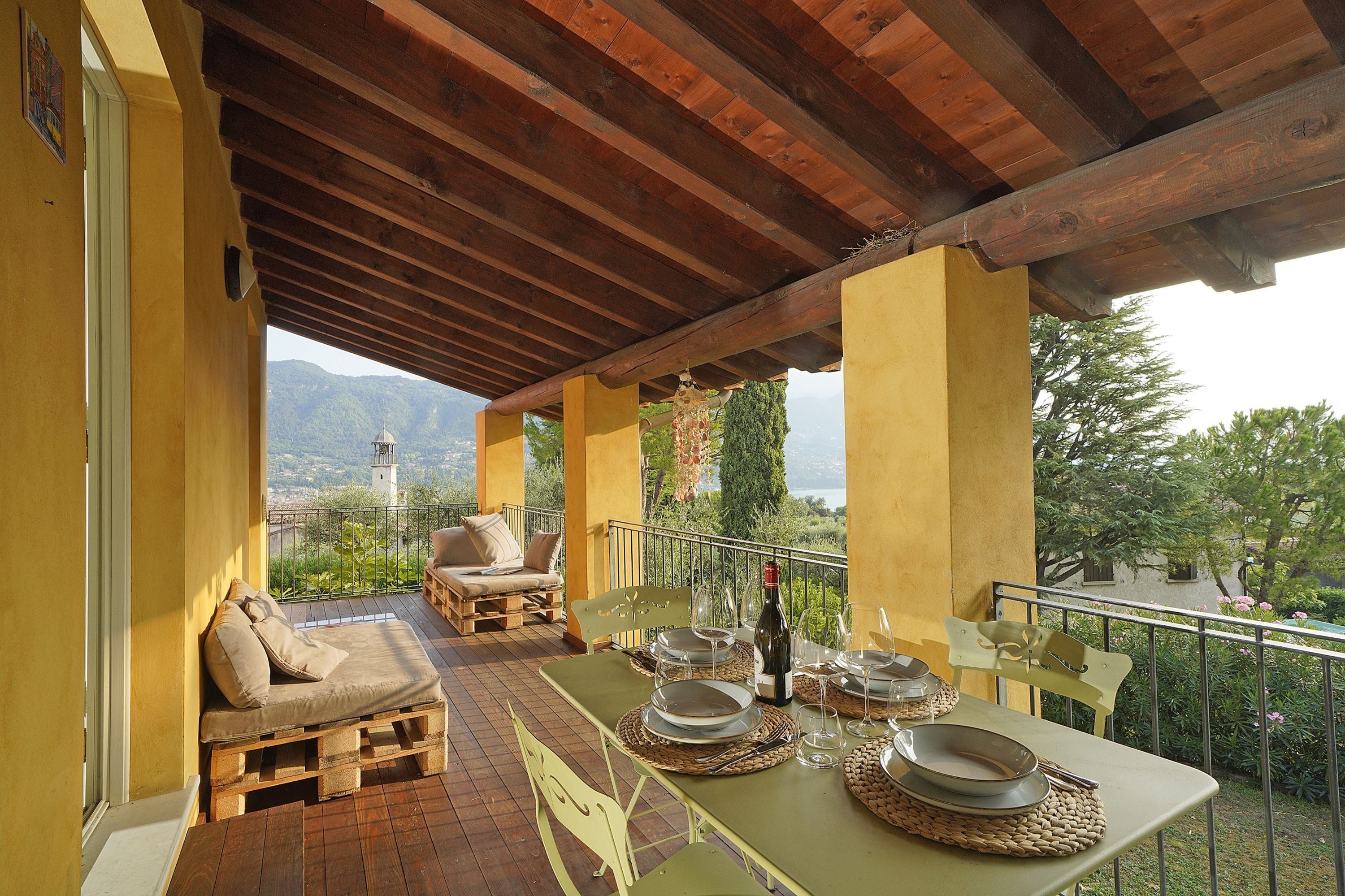 An outdoor dining area with a table set for two, a wooden bench, and a view of the mountains.