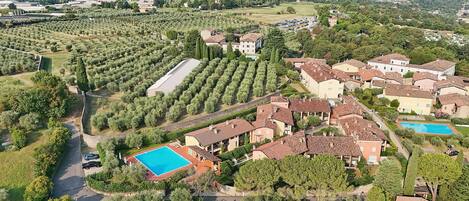 Vue aérienne d’un quartier résidentiel avec une piscine, des jardins en terrasses et différents types de bâtiments.