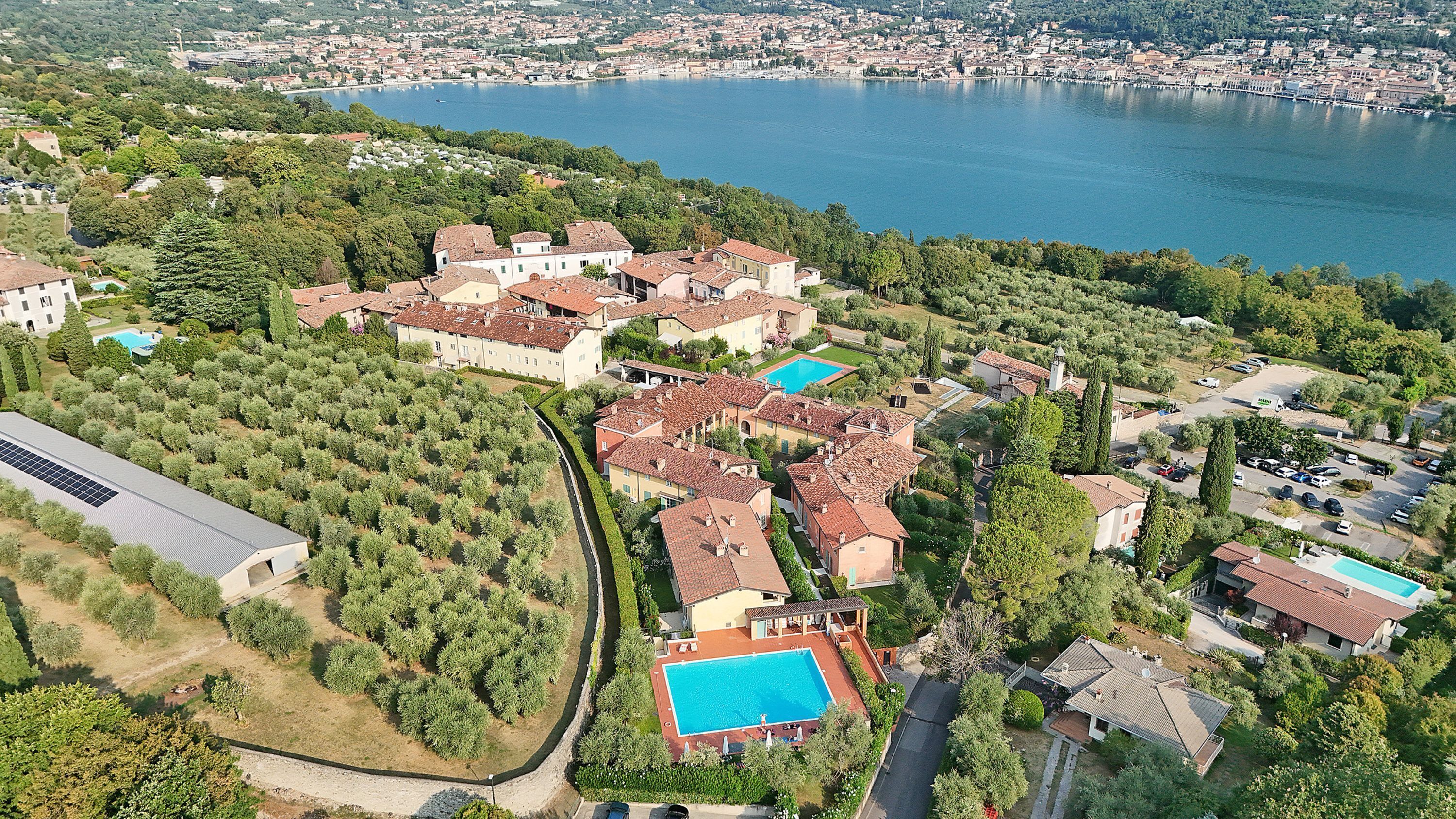 A residential area with multiple houses, a swimming pool, and a large body of water in the background.