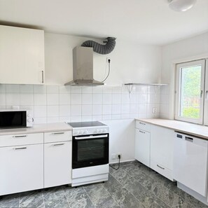 A kitchen with white cabinets, a microwave, an oven, and a window.