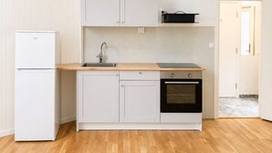 A compact kitchen with a refrigerator, sink, oven, and a small countertop. - Bokloster Longstay (Stockholms län)