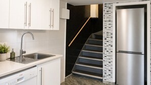 A modern kitchen with white cabinets, a stainless steel sink, and a built-in dishwasher. - Bokloster Longstay (Stockholms län)
